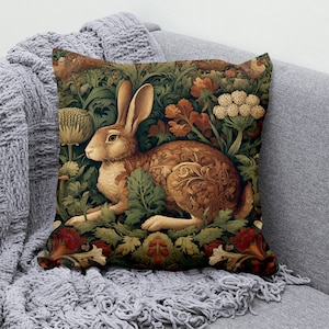 May include: A decorative throw pillow featuring a brown rabbit surrounded by intricate floral patterns in shades of green, red, and gold. The rabbit is depicted in a stylized art nouveau style.