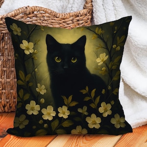 May include: Square throw pillow featuring a black cat with yellow eyes, surrounded by yellow flowers and green leaves. The cat is centered on a dark background, creating a striking contrast. The pillow is likely made of a soft fabric.