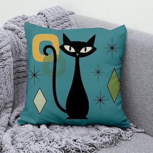 Op de afbeelding: Teal sierkussen met een zwarte kattenillustratie in een mid-century modern stijl. De kat heeft een lange, gebogen staart en staat tegen een achtergrond met geometrische vormen in geel, groen en wit. Decoratieve sterren en ruitvormen maken het ontwerp compleet.