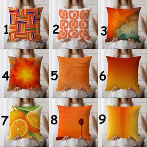 May include: Nine decorative throw cushions with diverse designs. The cushions display vibrant colours and patterns, including geometric shapes, abstract art, and fruit illustrations. The colour palette includes orange, yellow, red, and blue.