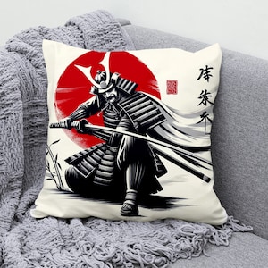 May include: A white throw pillow featuring a black and white illustration of a samurai warrior wielding a sword. The warrior stands before a red sun, with the Japanese characters "侍" and "道" inscribed in red on the right side of the pillow.
