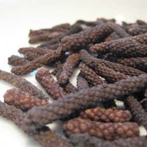 May include: A close-up of a pile of dried long peppercorns. The peppercorns are dark brown and have a wrinkled texture.