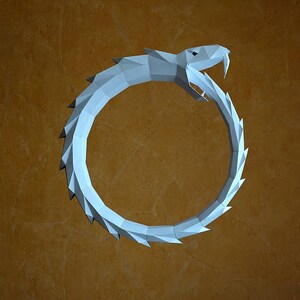 Può includere: Un serpente di origami di carta bianca a forma di cerchio, su uno sfondo marrone.