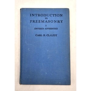 May include: A blue hardcover book titled Introduction to Freemasonry I Entered Apprentice by Carl H. Claudy. The front cover features a textured blue fabric finish with dark blue printed text centered on the front of the book.