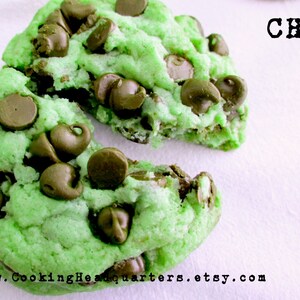 Può includere: Primo piano di due biscotti verdi e con gocce di cioccolato spezzati a metà. I biscotti sono su una superficie bianca con il testo "CHQ" in lettere nere sopra di loro. Il testo "www.CookingHeadquarters.etsy.com" è sotto i biscotti.