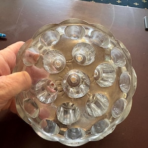 May include: A clear glass and metal decorative bowl with a scalloped edge. The bowl has a silver-coloured metal base and clear glass inserts. The bowl is round and has a series of clear glass inserts that are evenly spaced around the bowl.
