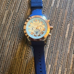 Pu&ograve; includere: Un orologio Mulco con cinturino in silicone blu e cassa in acciaio inossidabile color oro. Il quadrante dell'orologio &egrave; azzurro con dettagli dorati e tre sotto-quadranti. L'orologio ha un datario a ore 6.