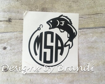 May include: Black and white vinyl decal of a fish jumping out of the water with a fishing hook and line in its mouth. The fish is circling a monogram with the letters "MSA".