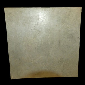 May include: A plain, light gray, square ceramic tile with a smooth surface. The tile has a few faint scratches.