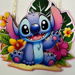 May include: A vibrant cake topper featuring the character Stitch amidst tropical flowers and the name "Avril". The number "6" is also included. The design is bright with pink, blue, yellow, and green hues, ideal for a birthday celebration.