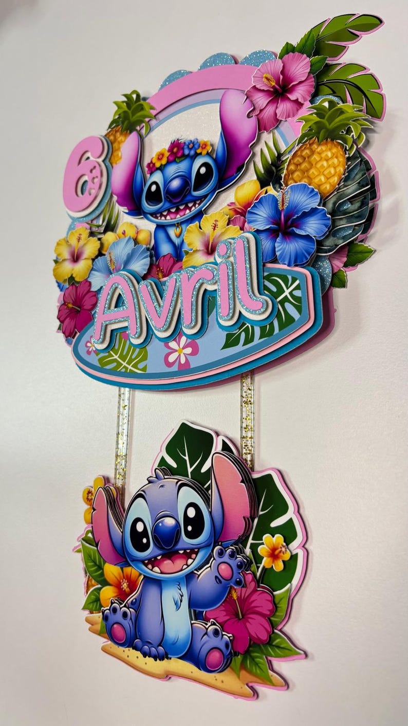 May include: A layered cake topper featuring the character Stitch from Lilo & Stitch. The topper includes the name "Avril" and the number "6", surrounded by tropical flowers, leaves, and pineapples. The design is colourful with pink, blue, yellow, and green accents.