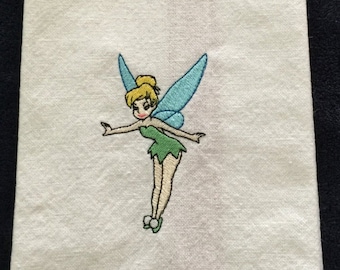May include: White kitchen towel with an embroidered image of Tinkerbell, a Disney fairy with green wings and a yellow dress.