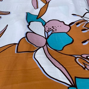 May include: A white fabric with a brown, pink, and blue floral pattern. The flowers are stylized and abstract.