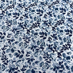 Könnte beinhalten: Weißer Stoff mit einem blauen Blumenmuster. Das Muster zeigt kleine Blumen und Blätter.
