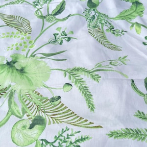 May include: White fabric with a green floral pattern. The pattern features leaves, flowers, and ferns.