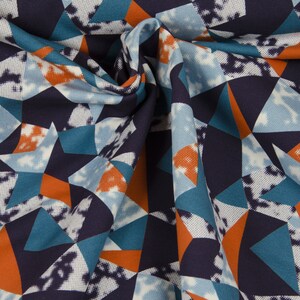 Könnte beinhalten: Ein Stoff mit einem geometrischen Muster in Blautönen, Orange und Weiß. Der Stoff ist gefaltet und zeigt das sich wiederholende Muster.
