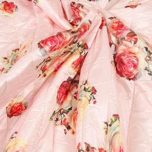 Könnte beinhalten: Rosa gesteppter Stoff mit einem Blumendruck mit rosa, roten und gelben Rosen. Der Stoff hat einen dezenten Glanz und eine weiche Textur.