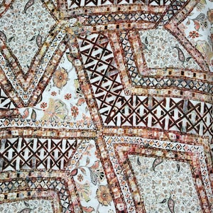 Könnte beinhalten: Ein weißer Stoff mit einem braunen, beige und grauen geometrischen Muster. Das Muster zeigt Paisley-Formen und komplizierte Designs.