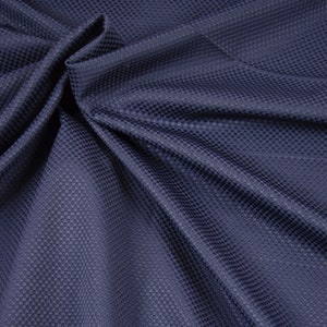 Könnte beinhalten: Nahaufnahme eines dunkelblauen Stoffes mit einem strukturierten, gewebten Muster. Der Stoff ist gefaltet und drapiert, wodurch die Textur und Tiefe des Materials sichtbar werden.