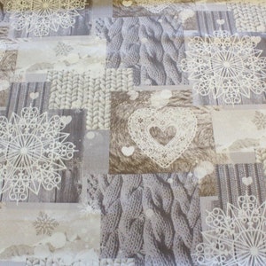 Könnte beinhalten: Ein beigefarbener Stoff mit Patchwork-Muster mit weißen Schneeflocken, Herzen und Strickmustern.