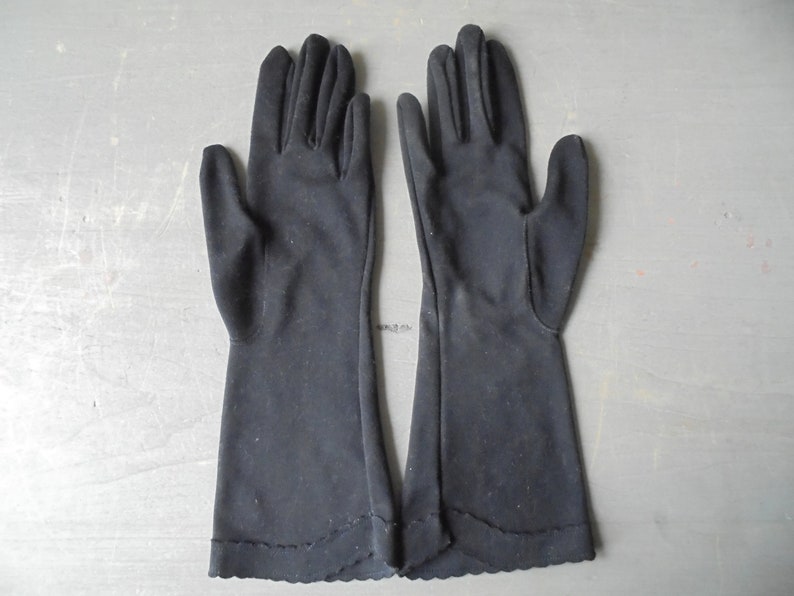 Peut inclure: Une paire de longs gants noirs avec un bord festonn&eacute;.