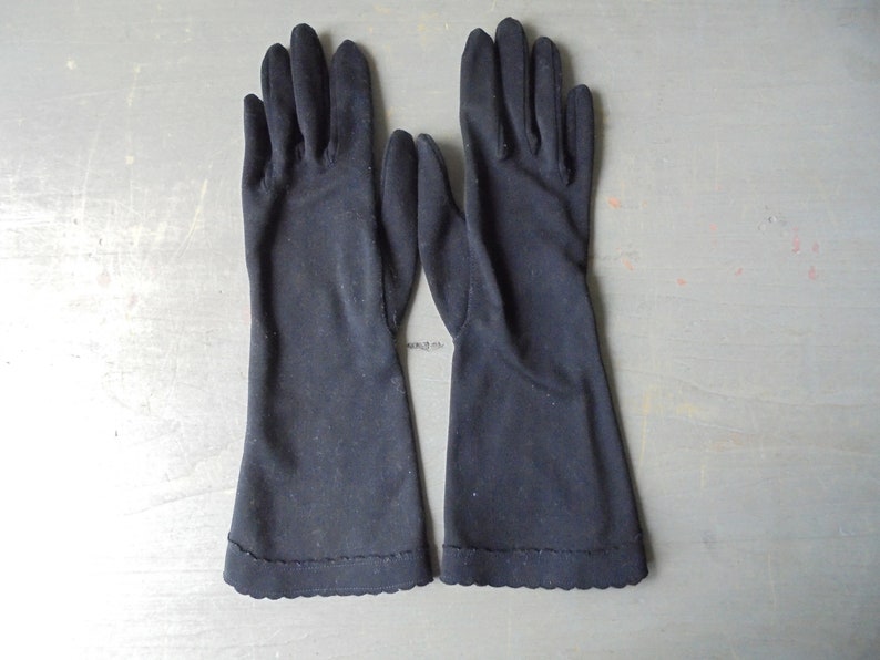 Peut inclure: Une paire de longs gants noirs avec un bord festonn&eacute;.