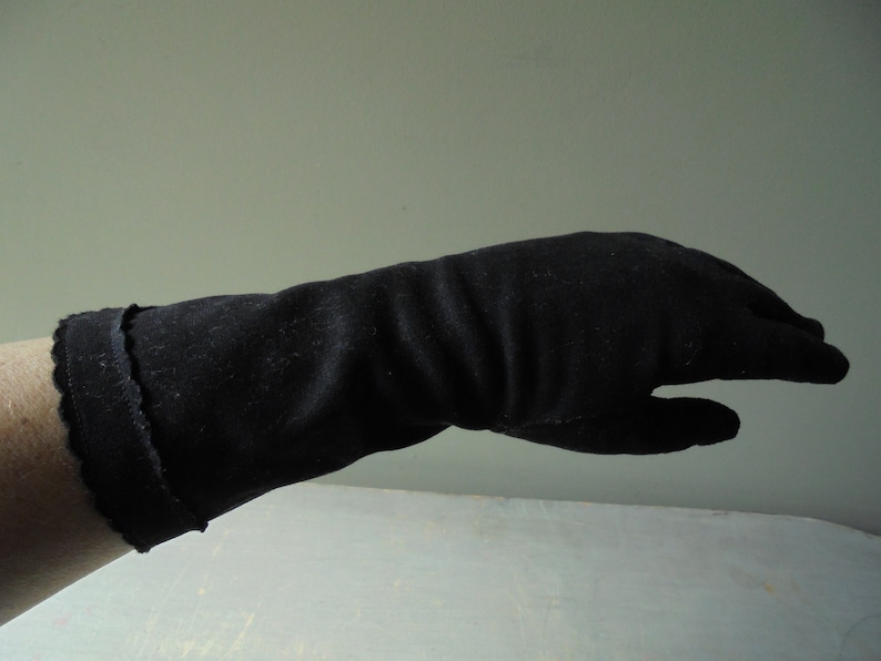 Peut inclure: Un long gant noir avec un bord festonn&eacute;.