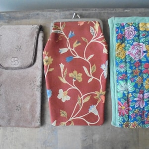 May include: Three different fabric pouches with floral patterns. The pouch on the left is brown with a small star pattern. The middle pouch is red with a floral pattern. The pouch on the right is blue with a floral pattern and a green border.