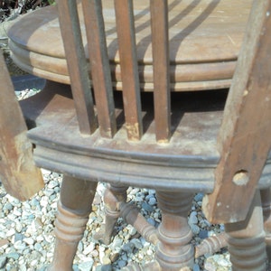 Pu&ograve; includere: Primo piano di una sedia di legno con lo schienale rotto. La sedia ha una seduta rotonda e gambe tornite. La sedia necessita di riparazione.