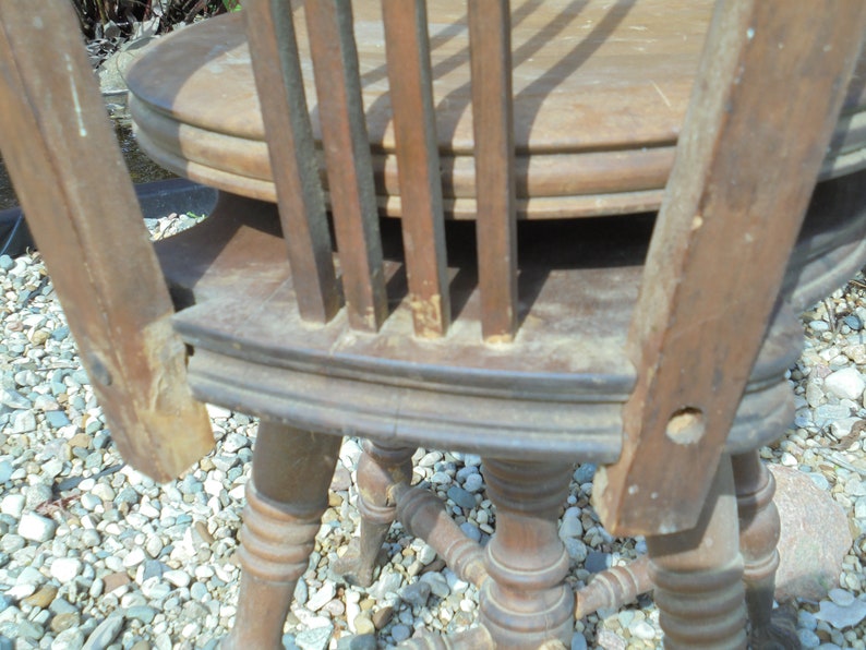 Pu&ograve; includere: Primo piano di una sedia di legno con lo schienale rotto. La sedia ha una seduta rotonda e gambe tornite. La sedia necessita di riparazione.