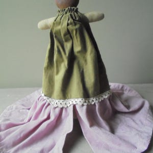 K&ouml;nnte beinhalten: Eine handgemachte Puppe mit einem braunen Kopf und einem gr&uuml;nen Kleid mit einer wei&szlig;en Spitzenborte. Die Puppe tr&auml;gt einen rosa Rock.
