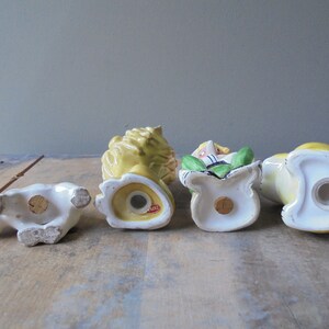 May include: A collection of four vintage ceramic salt and pepper shakers. The shakers are in the shape of a polar bear, a lion, a person in a bag, and a duck. The colors are white, yellow, green, and red.