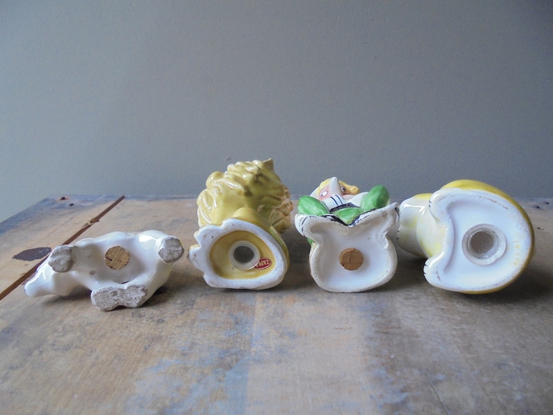 May include: A collection of four vintage ceramic salt and pepper shakers. The shakers are in the shape of a polar bear, a lion, a person in a bag, and a duck. The colors are white, yellow, green, and red.
