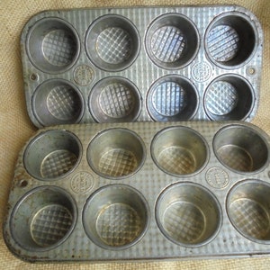 May include: Two vintage metal muffin tins with a textured surface. Each tin has 6 individual muffin cups.