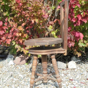 Pu&ograve; includere: Uno sgabello in legno regolabile in altezza con finitura marrone e quattro gambe. Lo sgabello &egrave; seduto su un letto di ghiaia.