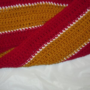 May include: A crocheted scarf with alternating stripes of red, white, and gold.