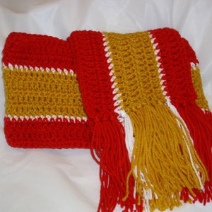 May include: A crocheted scarf with red, gold, and white stripes and long fringe.