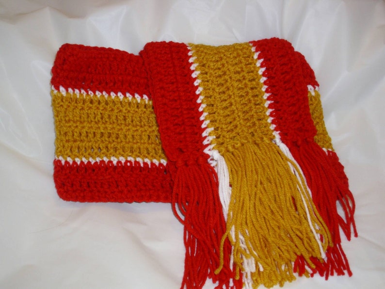 May include: A crocheted scarf with red, gold, and white stripes and long fringe.