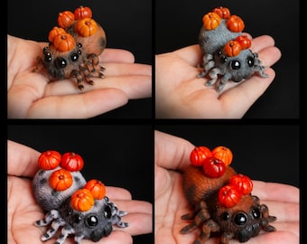 May include: Four small spider figurines with textured bodies and multiple black eyes. Each spider features several miniature orange pumpkins attached to its back. The spiders are shown in different colour variations including brown and grey tones.