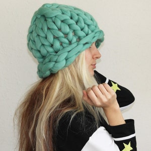 Puede incluir: Un gorro de punto grueso de color azul turquesa. El gorro est&aacute; hecho con hilo grueso y tiene un ajuste holgado.
