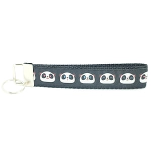 May include: Black key chain with a repeating pattern of panda faces. The key chain has a silver key ring.