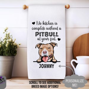 May include: White kitchen towel with a brown and white pitbull dog illustration. The text on the towel reads "No kitchen is complete without a pitbull at your feet." The dog's name "JOHNNY" is printed below the illustration. The text "SCROLL TO SEE ADDITIONAL BREED IMAGE OPTIONS!" is printed at the bottom of the towel. The text "PERSONALIZE ME!" is printed on a white circle.