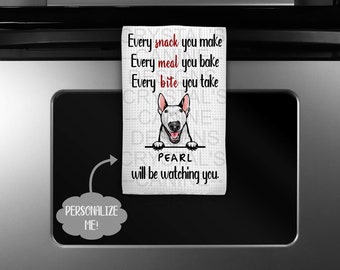 Puede incluir: Paño de cocina blanco con una ilustración de perro Bull Terrier y el texto "Every snack you make, Every meal you bake, Every bite you take. PEARL will be watching you." El paño está colgado de un electrodoméstico negro.