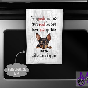 May include: White kitchen towel with a printed design featuring a black and brown dog and the text "Every snack you make, Every meal you bake, Every bite you take, NOVA will be watching you." The towel also has the text "PERSONALIZE ME!"