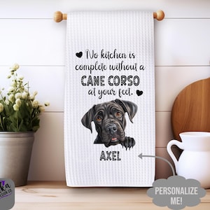 May include: White kitchen towel with a waffle weave texture, featuring a Cane Corso dog illustration and the text "No kitchen is complete without a Cane Corso at your feet." The dog's name, Axel, is printed below the image.