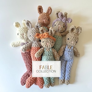 May include: A collection of six crocheted bunny plushies in various colours, including beige, brown, light blue, light green, and pink. The plushies are arranged in a circle with the text "FABLE COLLECTION" in the centre.