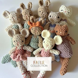 May include: A group of crocheted stuffed animals in various colors, including brown, white, pink, and green. The animals are arranged in a pile, with the text "FABLE COLLECTION" visible in the lower center of the image.