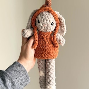 May include: A handmade crochet bunny doll with a light gray body, long ears, and a rust-colored hooded dress. The doll has black safety eyes and is approximately 10 inches tall.