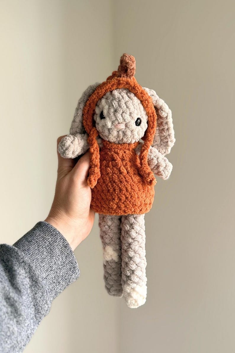 May include: A handmade crochet bunny doll with a light gray body, long ears, and a rust-colored hooded dress. The doll has black safety eyes and is approximately 10 inches tall.
