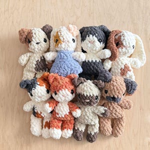 Puede incluir: Una colección de ocho pequeños animales de peluche tejidos a mano con ganchillo, con varios patrones de colores que incluyen blanco, marrón, gris, naranja y calicó. Cada juguete suave tiene un acabado de hilo texturizado y rasgos faciales.